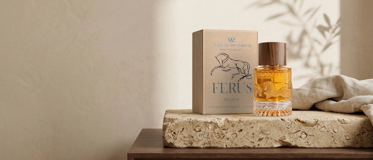 Un modèle tenant le parfum Ferus à la lumière du soleil, avec le flacon et son écrin au premier plan.